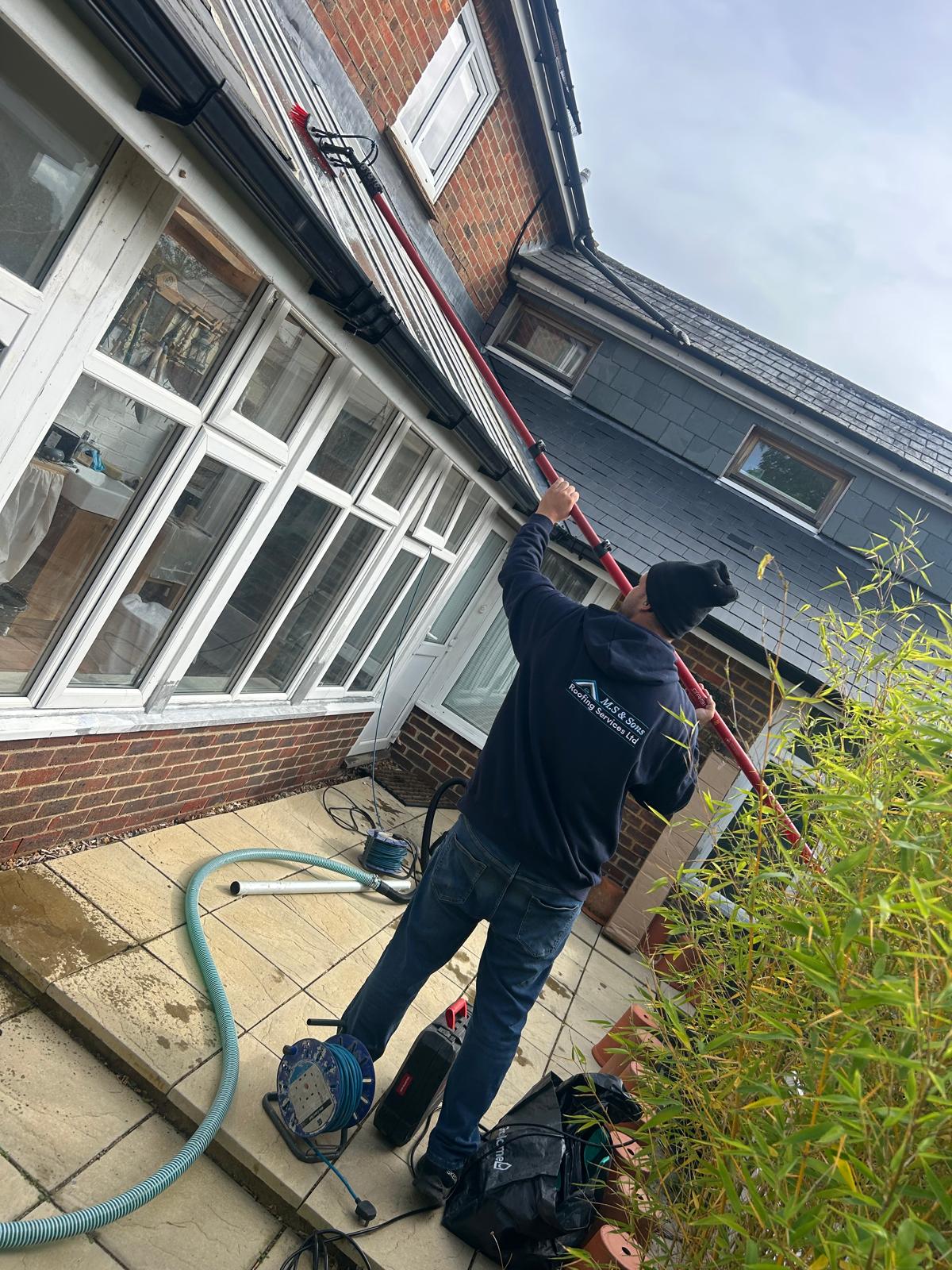 Technician cleaning a conservatory roof with a reach brush