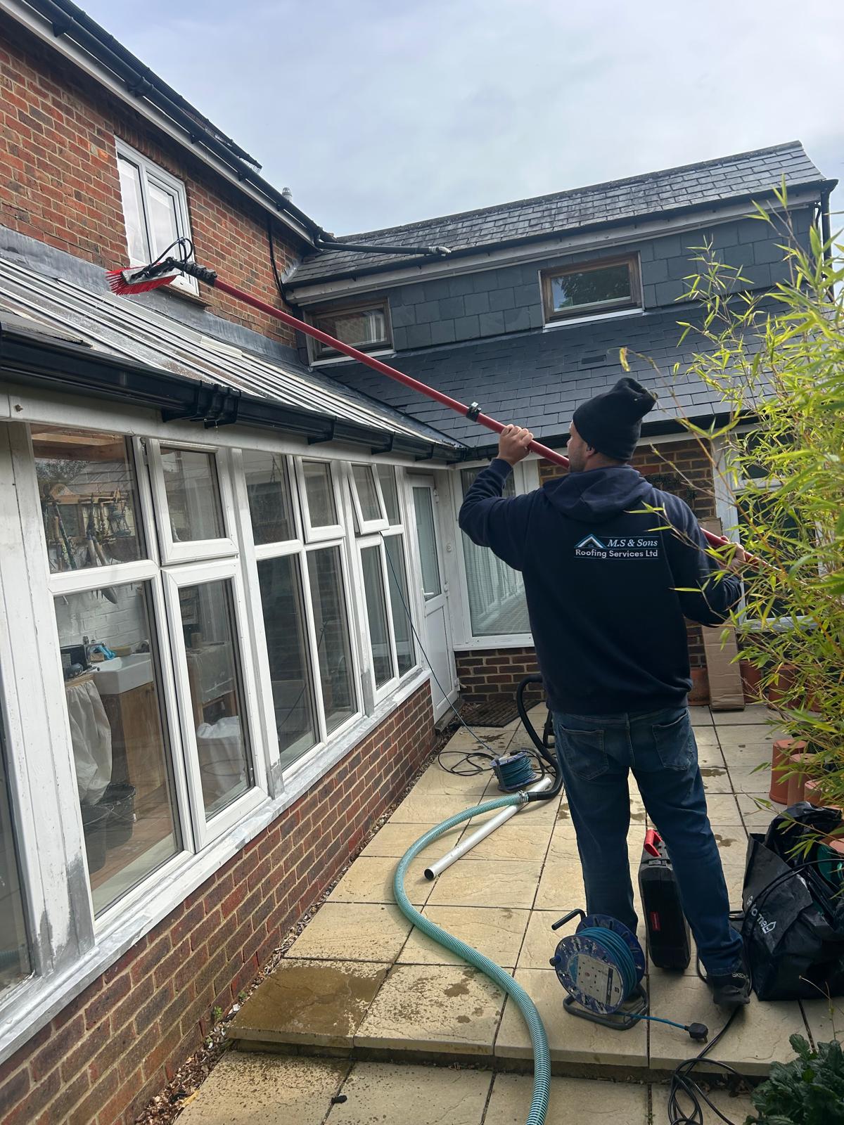 Technician cleaning a conservatory roof and gutter
